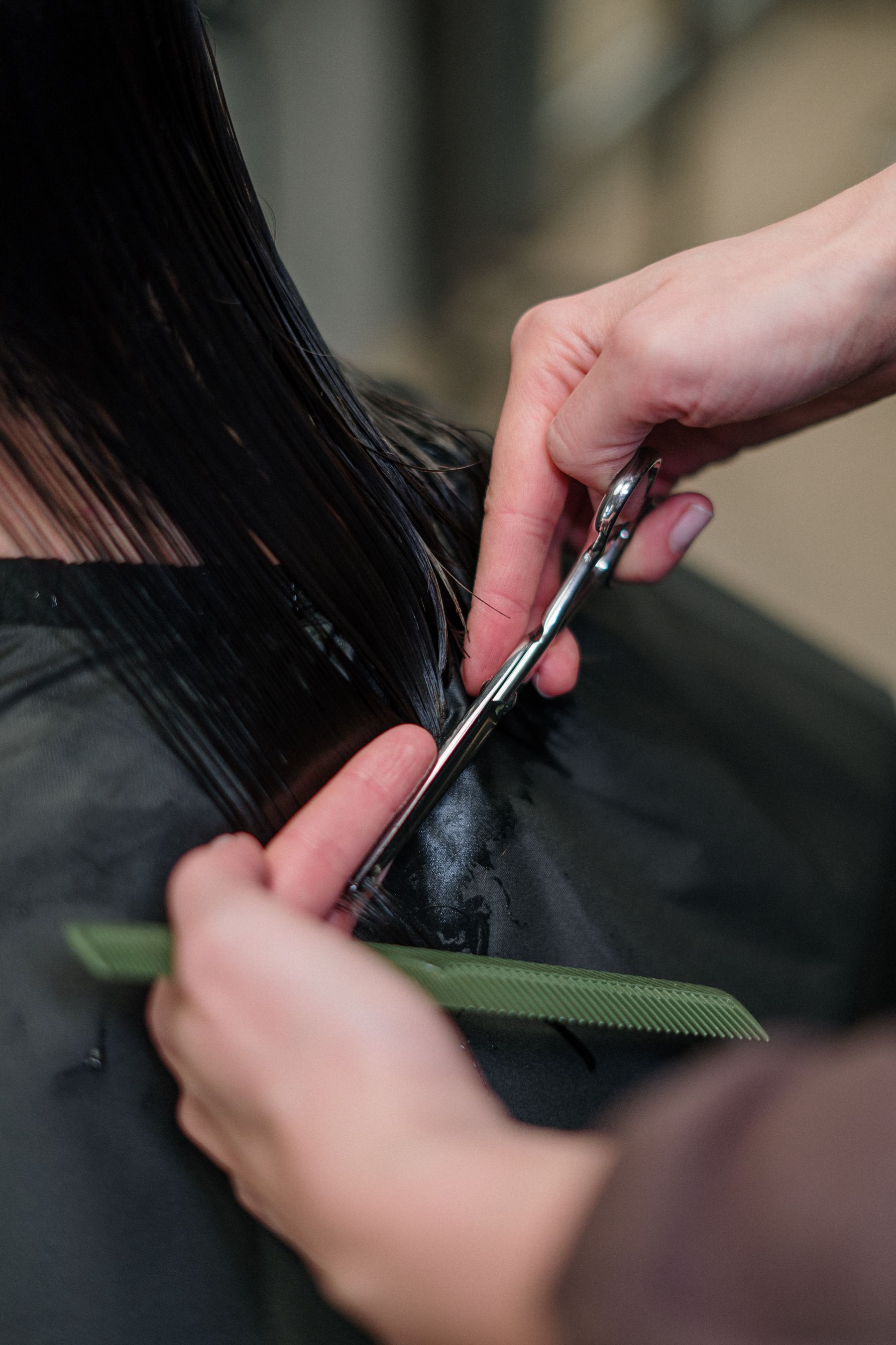 Close-up of scissors trimming dark hair