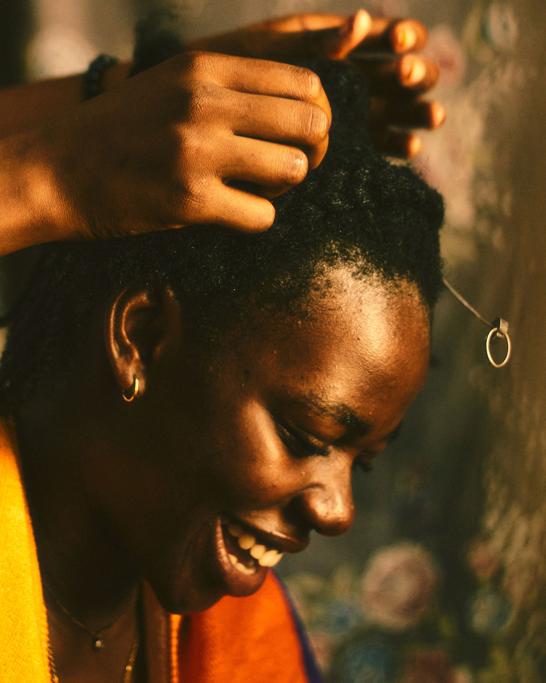 Smiling woman having her hair braided in warm light
