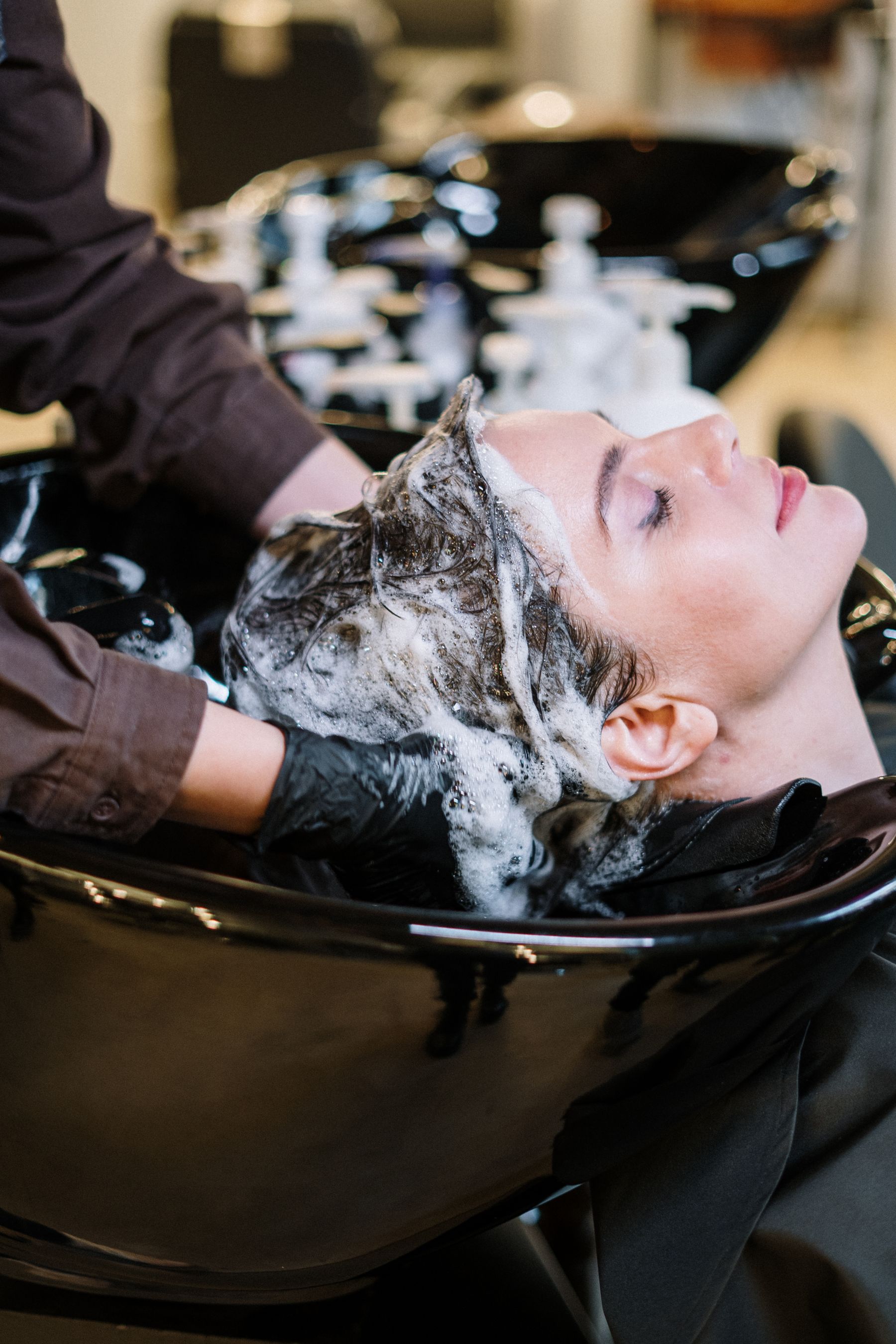 Client relaxing during a hair wash at a basin